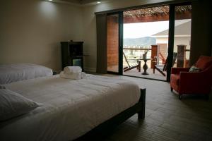 a bedroom with a bed and a chair and a large window at Entrevalle Hotel Boutique in Valle de Guadalupe