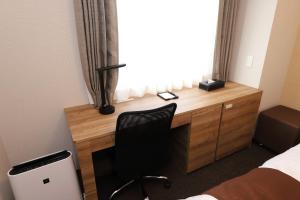 a bedroom with a desk with a chair and a window at Smile Hotel Premium Osaka Higashishinsaibashi in Osaka