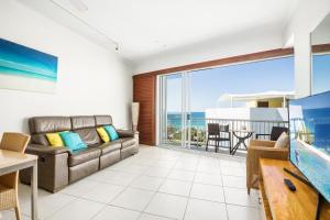 a living room with a couch and a view of the ocean at Rolling Surf Resort in Caloundra