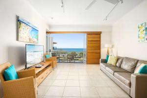 a living room with a couch and a television at Rolling Surf Resort in Caloundra