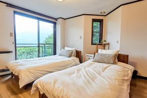 two beds in a room with a large window at Chalet Itomic M in Hakone