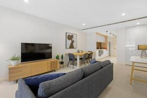 a living room with a couch and a flat screen tv at YARRA · YARRA Toorak Rd & Chapel St. Pool, Gym & Parking in Melbourne