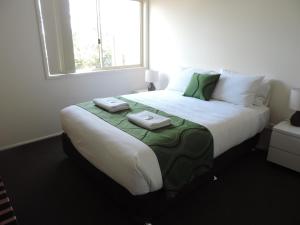 a bedroom with a large bed with two towels on it at Sussex Shores in Sussex inlet