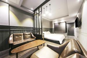 um quarto de hotel com uma cama, um sofá e uma cadeira em Masan Almond Hotel em Changwon