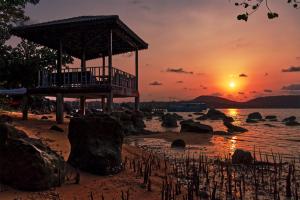 a pier on the beach with the sunset in the background at Samloem Laguna Resort in Koh Rong Sanloem