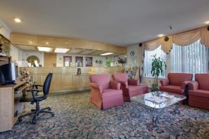 ein großes Wohnzimmer mit rosa Stühlen und einem Tisch in der Unterkunft Days Inn by Wyndham Gilroy in Gilroy