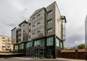 un alto edificio con finestre in vetro in città di Shera Park Boutique Hotel a Almaty