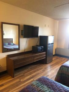 Zimmer mit einem TV, einem Kühlschrank und einem Spiegel in der Unterkunft Luxury Inn in Cheyenne