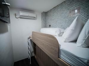 a bedroom with a bed with white pillows and a brick wall at King Wow Inn in Tainan