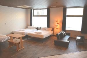 um quarto com duas camas e uma cadeira e uma mesa em Economy Hotel Upashi em Asahikawa
