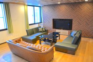 uma sala de estar com um sofá e cadeiras e uma televisão em Economy Hotel Upashi em Asahikawa