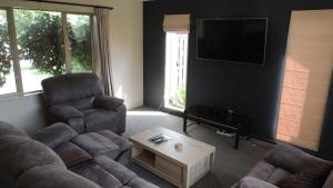 a living room with a couch and chairs and a tv at Airport, motorway, shopping handy in Christchurch