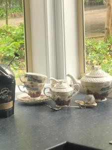 a table with three tea cups and a bottle of wine at Toolebewang Farm Cottage in Launching Place