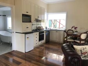 a kitchen with white cabinets and a couch and a table at Toolebewang Farm Cottage in Launching Place