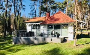 a small white house with a deck in the grass at Ferienhaus Hanna in Waren