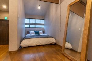 een kleine slaapkamer met een bed met een spiegel bij ビジュースイーツ Century in Osaka