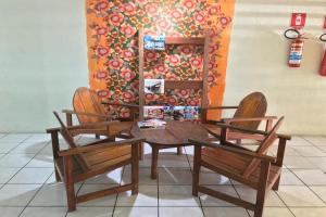 a wooden table and two chairs and a wall with flowers at Hotel Recanto Do Sol in Porto Seguro