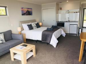 Kaka Point Views Apartment 2 في كاكا بوينت: غرفة نوم بسرير واريكة ومطبخ