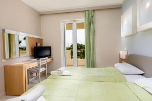 a bedroom with two beds and a desk and a television at Sovereign Beach Hotel in Kardamaina