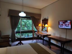 a bedroom with a desk and a table and a window at New Grand Park Hotel in Surabaya