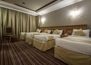 a hotel room with three beds and a television at EWG Rahaf Al Mashaer Hotel in Mecca