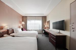 a hotel room with two beds and a desk with a television at Best Western Premier Gangnam Hotel in Seoul