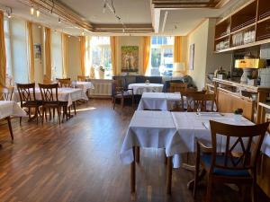 un restaurante con mesas y sillas con mantel blanco en Landhaus Hechtsberg, en Hausach