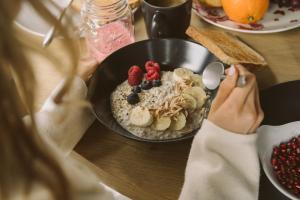 una mujer sentada en una mesa con un tazón de avena con fruta. en The HEY HOTEL, en Interlaken