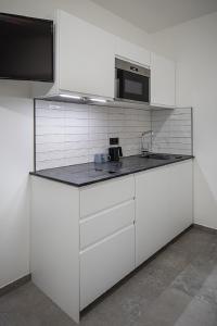 a white kitchen with a sink and a microwave at Home & Work in Pulheim
