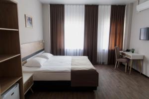 um quarto de hotel com uma cama, uma secretária e uma janela em Отель "Даймонд Луговая" em Kursk