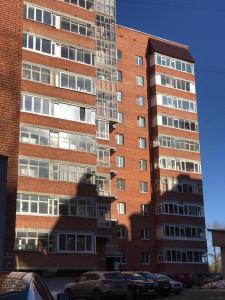 a tall brick building with cars parked in front of it at ОК! Красноармейская, 151 in Tomsk