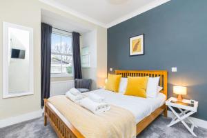 una camera da letto con un grande letto con cuscini gialli e una finestra di Morleys Rooms - Located in the heart of Hurstpierpoint by Huluki Sussex Stays a Hurstpierpoint