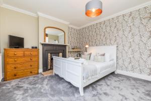 a bedroom with a white bed and a fireplace at Morleys Rooms - Located in the heart of Hurstpierpoint by Huluki Sussex Stays in Hurstpierpoint