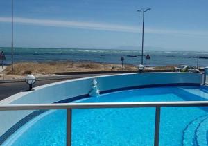a blue swimming pool with the ocean in the background at OCEANPEARL 209 in Strand