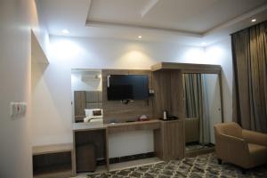 una camera d'albergo con TV e specchio di فندق الوردة الجميلة a Abha Altre 21 foto
