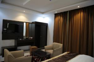 una stanza d'albergo con un letto e due sedie di فندق الوردة الجميلة a Abha