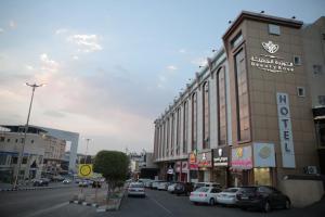 una strada cittadina con auto parcheggiate di fronte a un edificio di فندق الوردة الجميلة a Abha