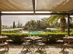 patio ze stołami i krzesłami oraz basenem w obiekcie Mas de Torrent Hotel & Spa, Relais & Châteaux w mieście Torrent