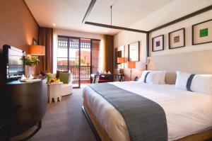 a hotel room with a large bed and a television at Hôtel Du Golf Rotana Palmeraie in Marrakesh