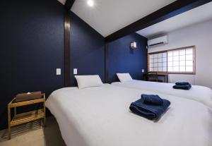 two white beds in a room with blue walls at Shiki Homes ZEN FUYACHO in Kyoto