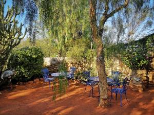 a table and chairs under a tree in a yard at Amber Lagoon Backpackers Lodge in Vleirivier