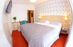 um quarto com uma grande cama branca num quarto em Hotel Flora em Mariánské Lázně