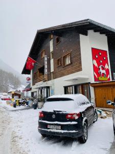 un coche cubierto de nieve frente a un edificio en Qi-Lin Hotel Restaurant, en Ayer