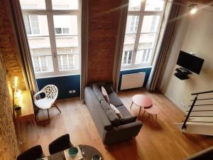 uma sala de estar com um sofá e 2 janelas grandes em Charmant appartement style Canut Pentes Croix Rousse em Lyon