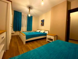 a bedroom with two beds with blue sheets at Апартамент РАЙНОВИ in Pleven