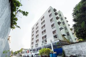 a tall white building with cars parked in front of it at Next Bird Suite SHA in Nonthaburi