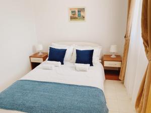 a bedroom with a large white bed with blue pillows at Apartments Sneki in Baošići