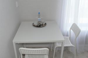 ウファにあるMini Hotel Evropaの白いテーブル(ボトル入り飲料水1本付)、椅子2脚
