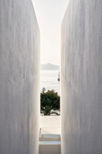 Cette chambre offre une vue sur l'océan à travers un mur blanc. dans l'établissement Myconian Korali Relais & Chateaux, à Mykonos