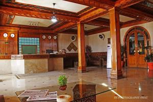 una gran sala de estar con techos de madera y una mesa. en Hotel Swat Regency, en Swat